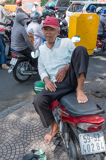 Ho Chi Minh, Vietnam - April 03, 2025: Motorcycle driver resting in the city center