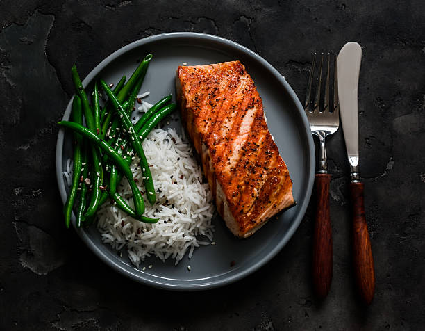 istock Healthy lunch - grilled salmon, basmati rice and green string beans on a dark background, top view 2213377122