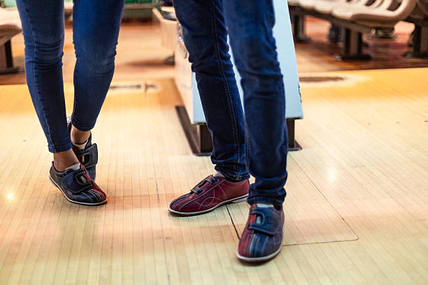 Two friends wearing colorful bowling shoes are preparing to enjoy a fun filled game at the bowling alley, ready for some friendly competition