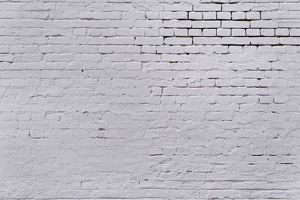 istock A brick wall covered with a thick layer of white paint. 2213382966