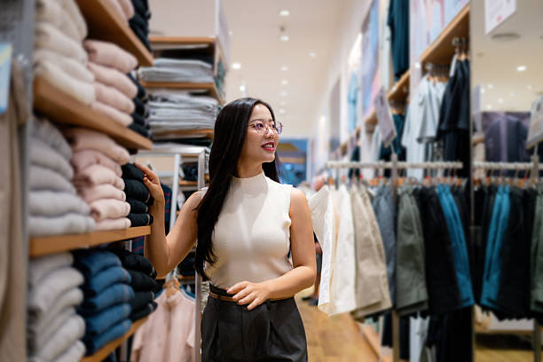 istock Smiling customer browsing through stylish clothes displayed on shelves and hangers in a vibrant fashion store, enjoying the shopping experience 2213383416