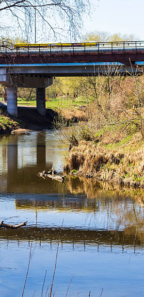 istock Yellow bus crossing the bridge, casting reflection in the water. Concept 2213387274