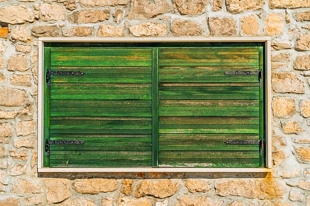 closed old green wooden window shutters on brick wall