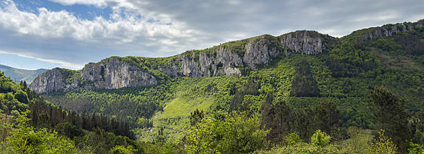 istock Majestic rock formations dominating lush green valley under cloudy sky. 2213394640