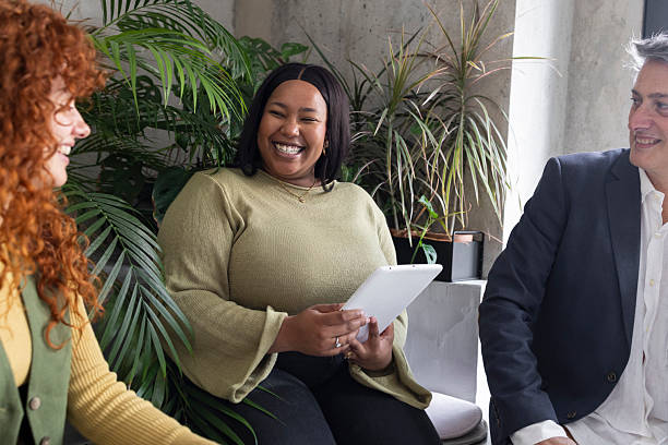 istock Coworkers using tablet and smiling during business meeting in modern office 2213399687