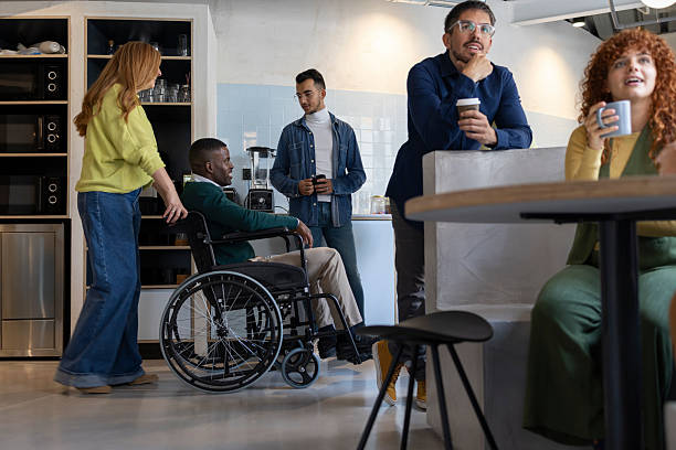 istock Diverse business team enjoying coffee break in modern office, including a disabled colleague 2213399700