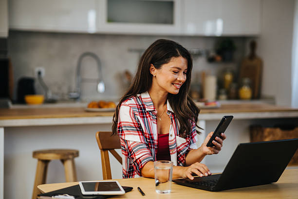 istock Smiling freelancer working from home using laptop and smartphone 2213401861