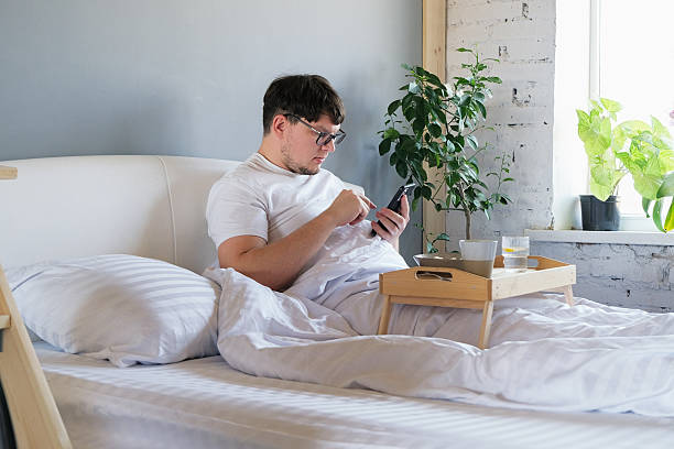 istock Young man waking up and having breakfast in bed and using smartphone 2213406173
