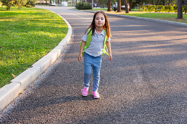 istock Young girl walking on park path with backpack on sunny day 2213410024