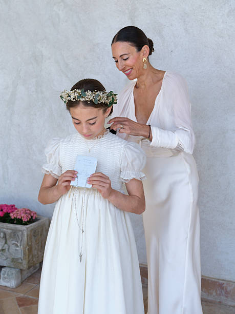 Mother helping her daughter with her floral headband, preparing for her first communion