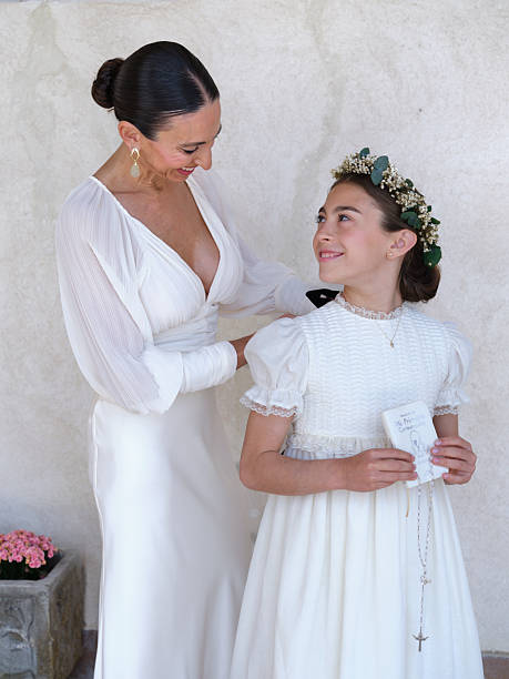Elegant mother fixing her daughter's communion dress before the ceremony
