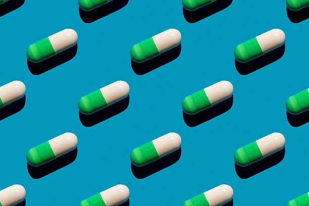 istock Pattern made with pharmaceutical medicine green white capsules on blue background. Medicine concept. 2213413062