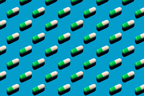 istock Pattern made with pharmaceutical medicine green white capsules on blue background. Medicine concept. 2213413063