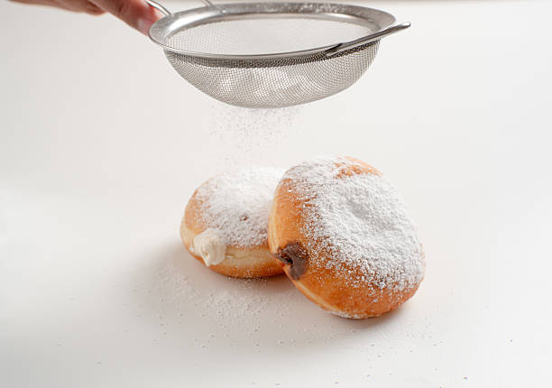 Powdered jelly-filled donuts with creamy fillings on white background – sweet pastry dessert perfect for bakery, breakfast, recipes, articles, snack-theme or any cooking content.