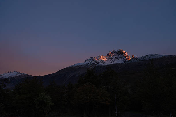 Cerro castillo mountain peak glowing orange and pink with alpenglow at sunrise, showcasing the breathtaking beauty of patagonia, chile