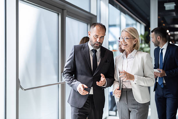 istock Two business people discussing documents in office hallway 2213421286