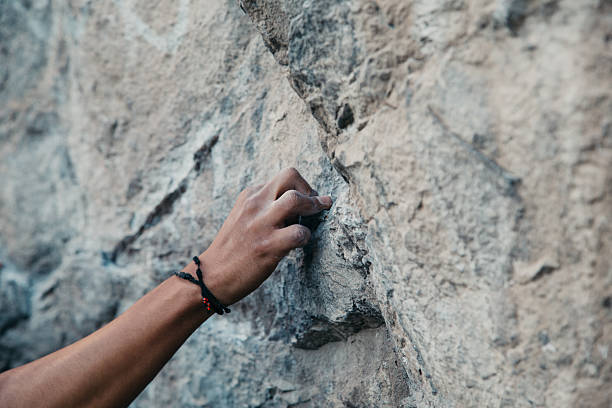 Rock climber grips a small hold on a challenging cliff face, demonstrating strength and determination