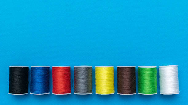 istock Colorful Spools of Thread Aligned on Vibrant Blue Background for Sewing Project Inspiration 2213428727