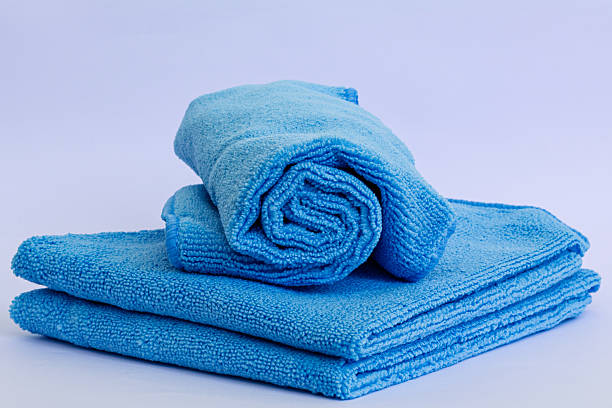 istock Rolled blue microfiber towel with low pile height on stack of towel isolated on white background 2213430970