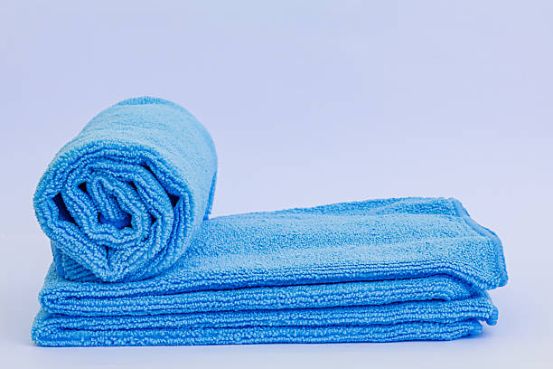 istock Rolled blue microfiber towel with low pile height on stack of towel isolated on white background 2213430974