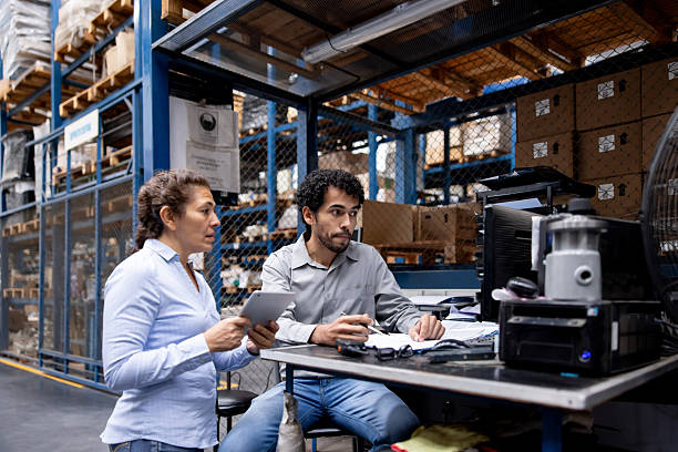 istock Employees working at a warehouse and looking at the inventory on the computer 2213436365