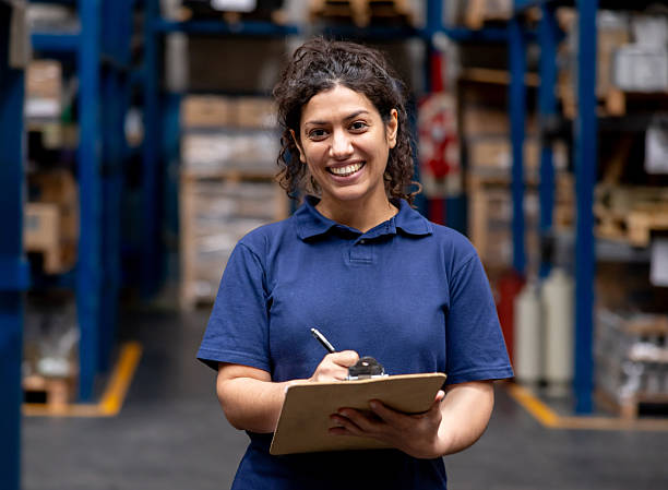 istock Woman working at a warehouse and smiling while holding a clipboard 2213436409