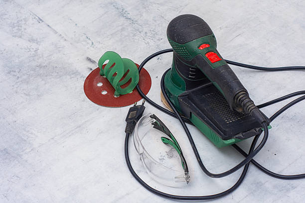 Closeup of green electric orbital sander on marble surface with sanding disk. Construction tool for renovation