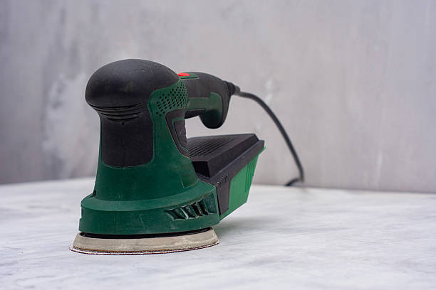 Closeup of green electric orbital sander on marble surface with sanding disk. Construction tool for renovation