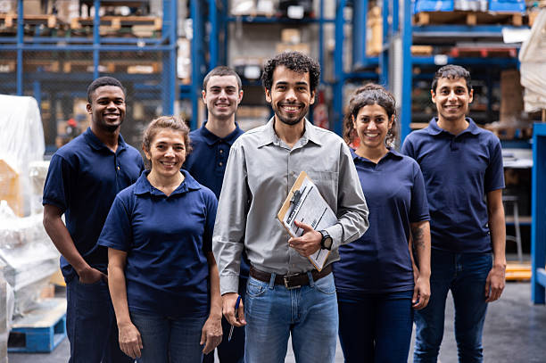 istock Happy team of warehouse workers smiling at work 2213438087
