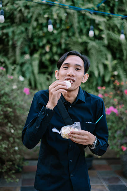 istock Man enjoying indonesian snack with lush greenery background and soft lighting 2213442566
