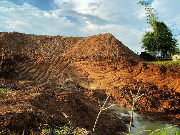 istock red earth excavation hole with tree branches under blue sky 2213447525