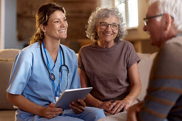 istock Happy female nurse using touchpad during a home visit at senior couple's home. 2213454071