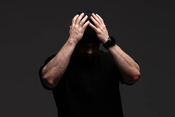 Man in black beanie and sweatshirt holding head