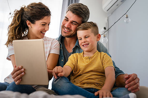 istock Parents with kid having fun online with application watching video cartoon or playing game on tablet 2213456473