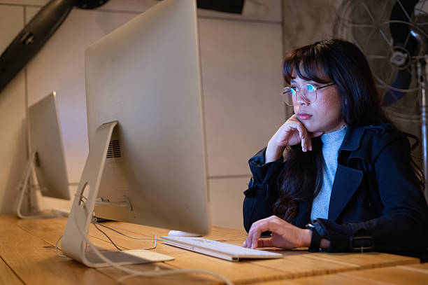 istock Young woman focused on computer screen working late in a creative office space 2213458068