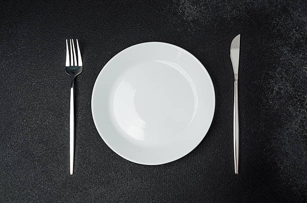 istock Cutlery arranged neatly beside a white plate on a dark surface 2213458739