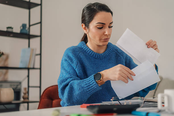 istock Woman opening mail at home office desk reading letter 2213458785
