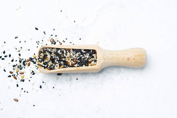 istock Wooden scoop filled with mixed seeds on a light surface for culinary use 2213458988
