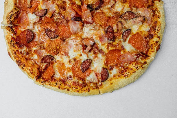 istock Delicious pizza topped with pepperoni and sausage on a white surface 2213459021