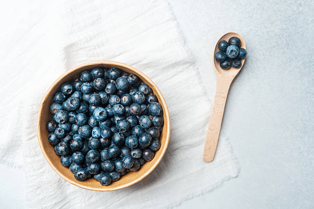 istock Fresh blueberries arranged in a wooden bowl on a light countertop 2213459034