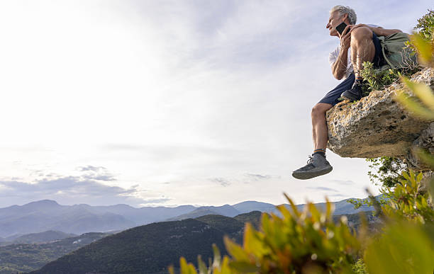 istock Mature man sits on cliff edge above mountains 2213461036