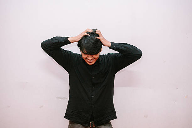 istock Frustrated young man pulling hair out in despair with white background 2213463306