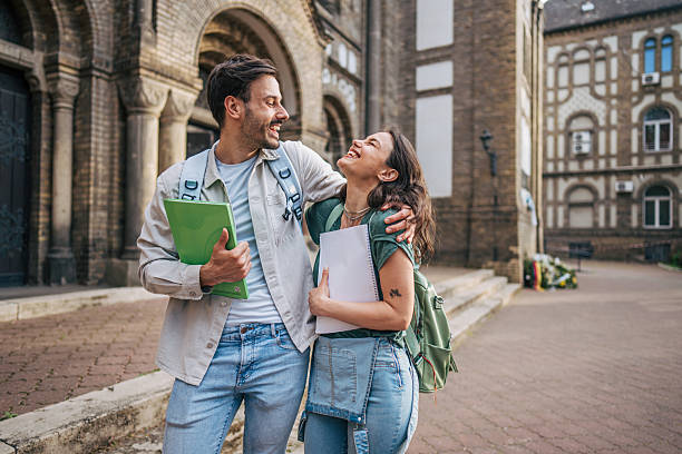 istock Two happy students laughing together outside university building 2213463844