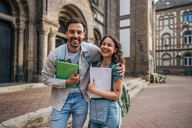 istock Two happy students smiling outside university building 2213463912