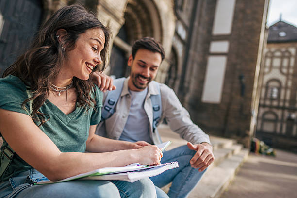 istock Two happy students studying together outdoors in urban setting 2213464396