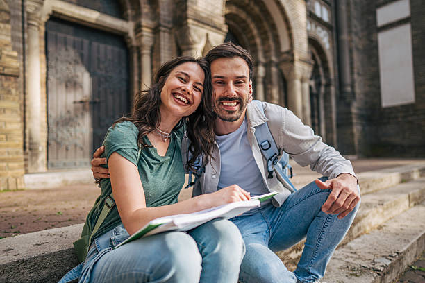Cheerful students studying together outdoors in front of university