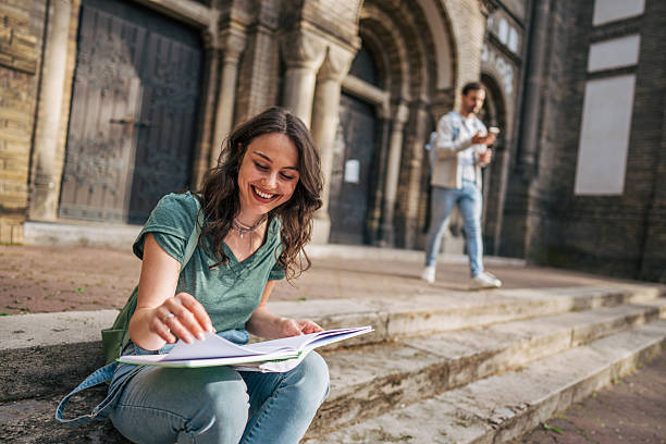 istock Smiling student studying on steps of university building 2213464606