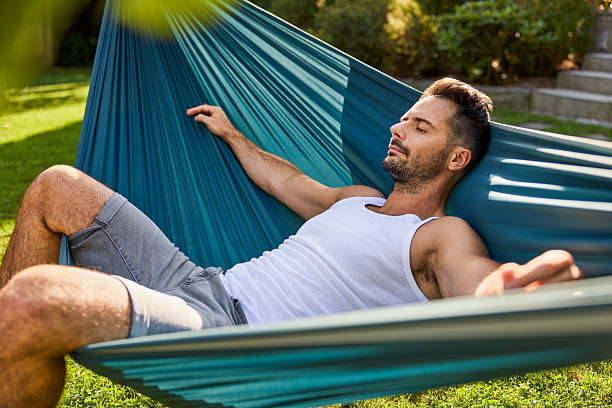 istock Adult man sleeping in hammock during summer afternoon in backyard 2213464637