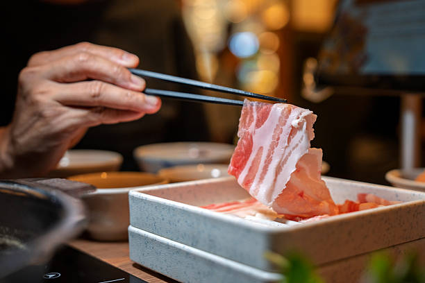 istock Hand Holding Raw Sliced Pork with Chopsticks 2213464653