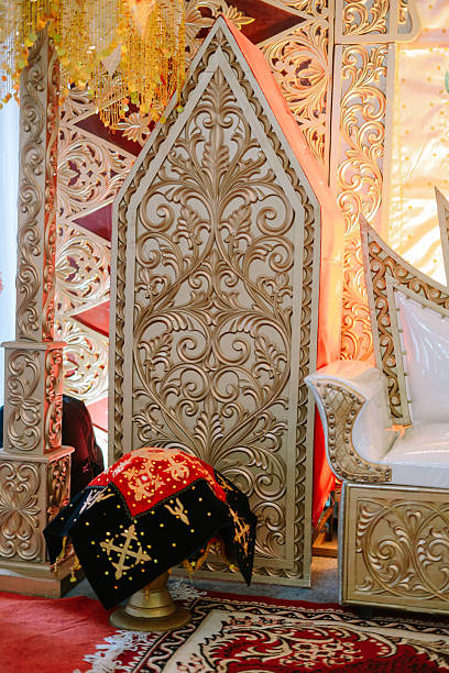Intricate floral carvings adorn stage decorations with rich gold tone and red accents adding an elegant touch to a celebratory event.